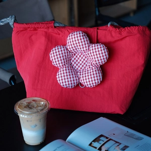 Detail of red floral tote bag with drawstring closure on a desk with a coffee cup