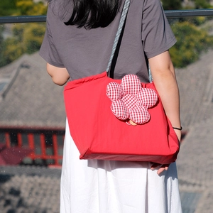 Detail view of red insulated lunch bag with a decorative fabric flower and woven straps