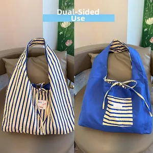 Detail of reversible shoulder bag showing blue stripes and solid fabric texture