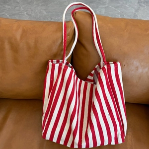 Detail showing the thick canvas texture and red-white diagonal stripes on the tote bag
