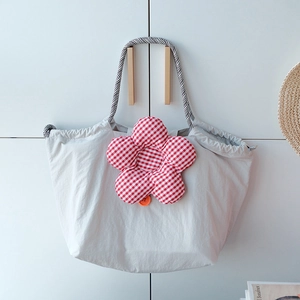Close-up of grey insulated lunch bag featuring red plaid flower and drawstring closure