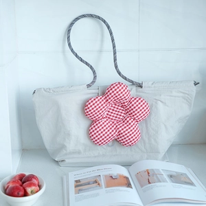 Detail of grey fabric lunch tote with large red gingham flower and braided rope handles