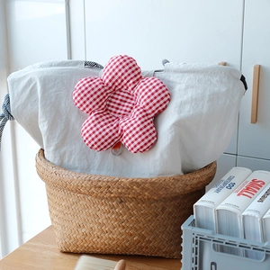Detail of insulated lunch bag with red plaid flower and striped handle in woven basket