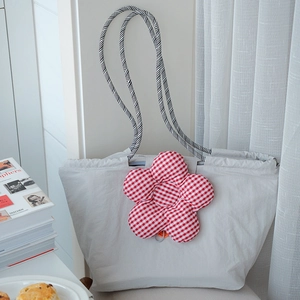 Detail of grey nylon lunch tote featuring a large red checkered flower plush charm