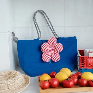 Close-up of royal blue canvas lunch bag with red checkered flower and braided rope handles