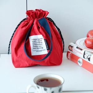 Detalle de bolsa térmica roja para el almuerzo con cordón ajustable y asas azules