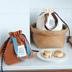 Detalle de bolsas de lona para almuerzo con cordón y asas dobles en dos combinaciones