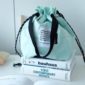 Vista detallada de la bolsa térmica verde menta con cordón sobre libros de diseño