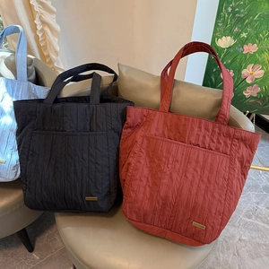 Dettaglio di borse tote trapuntate in nero, bordeaux e blu con tasche frontali