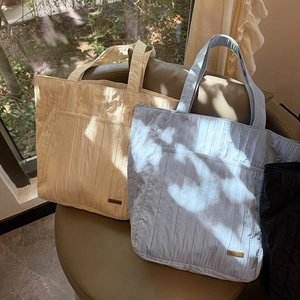 Dettaglio della borsa tote in nylon trapuntato con tasca frontale e targa in metallo
