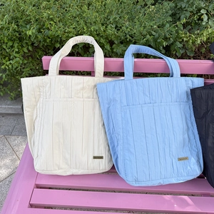 Dettaglio borse shopper a pieghe beige e blu con tasca frontale e decorazione dorata