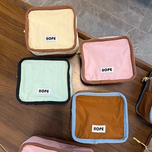 Flat lay of colorful nylon cosmetic bags with HOPE label on a dark wood background