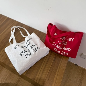Detail of canvas tote bags in white and red showing the star-themed printed quote