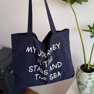 Detail of navy nylon tote bag featuring white artistic calligraphy script slogan