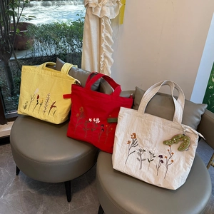 Close-up of three vintage nylon tote bags with floral embroidery and cute plush pendant