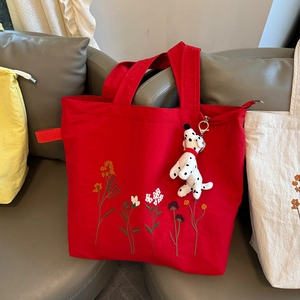 Macro detail of red nylon tote bag with floral embroidery and cute puppy charm