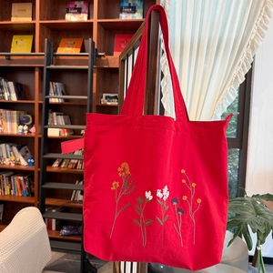 Detailed embroidery of colorful flowers on a red nylon tote bag with high-quality texture