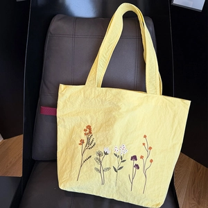 Detailed view of colorful floral embroidery on the lemon yellow canvas tote bag