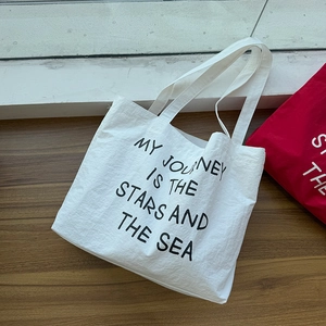 White canvas tote bag with black typography print on a wooden floor background