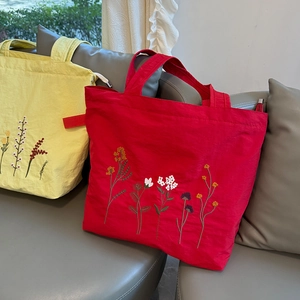 Floral embroidered nylon tote bag with zipper closure shown in yellow and red colors