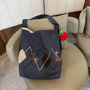 Detail of blue denim tote bag with argyle embroidery and cute strawberry plush charm