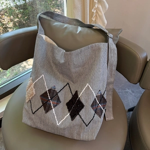 Detail of striped canvas tote bag with argyle patchwork on a green leather chair