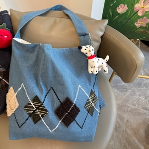 Close-up of light blue denim tote with diamond embroidery and puppy charm detail