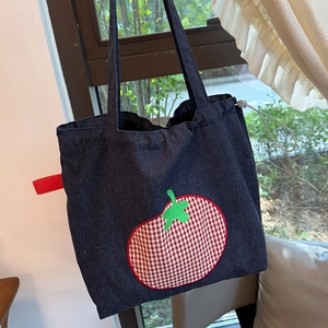 Detail of denim tote bag showing red checkered tomato patch and green embroidery