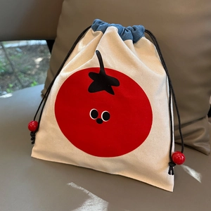 Detail showing canvas drawstring bag with denim patchwork and red tomato embroidery