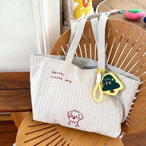Detailansicht der Canvas-Tasche mit Fischgrätmuster, Stickerei und Plüschanhänger