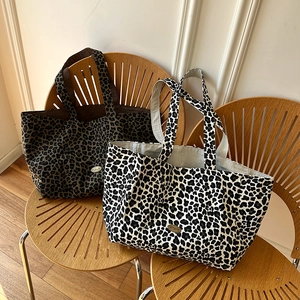Detailed view of handmade leopard print canvas tote bags on minimalist wooden chairs