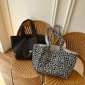Close-up of leopard print canvas tote bags in brown and beige colors on a wooden chair