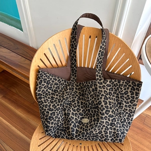 Close-up of leopard print canvas tote bag featuring an oval handmade metal badge