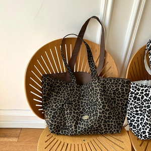 Detail view of leopard print canvas tote bag with metal logo on high-quality fabric