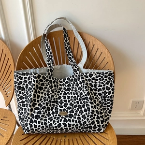 Close-up of handmade metal oval logo on leopard print canvas tote bag texture