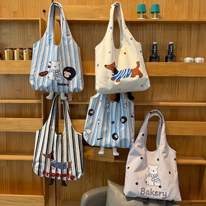 Detail of cartoon animal canvas tote bags with bread illustrations on a wooden shelf
