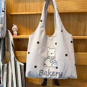 Detail shot of canvas tote bag featuring a cute cartoon bear print and black polka dots