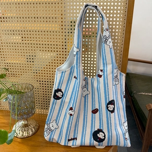 Close-up of blue and white striped canvas tote bag featuring a cute bear and bakery print