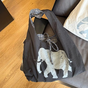 Close-up of black tote bag with white elephant print and checkered inner lining details