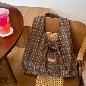 Detail view of the vintage plaid tote bag with brown leather label and wool texture