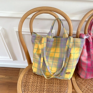 Close-up of a large purple and yellow checkered tote bag on a woven rattan chair