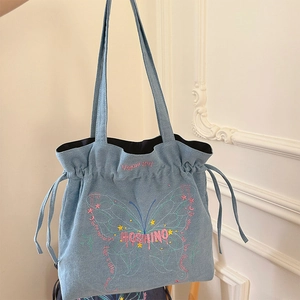 Detail of light blue denim tote bag with pink bow embroidery and drawstring side