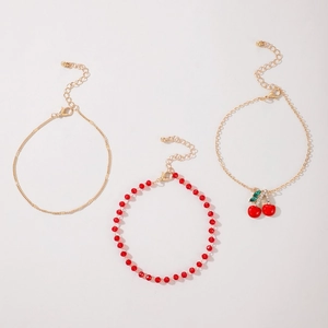 Three-piece layered anklet set with red beads, gold chains, and sparkling cherry charms