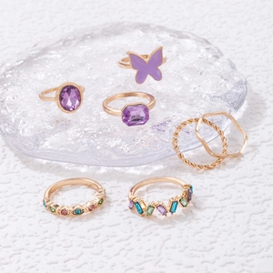 Detailed view of 7-piece gold ring set with purple butterfly stones and twisted bands
