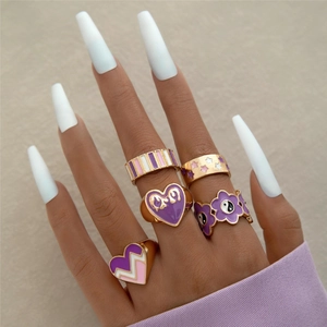 Detailed view of five-piece gold alloy ring set with purple enamel butterfly and star motifs