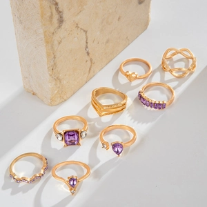 Detail of 8-piece gold-tone ring set featuring purple gemstones and sparkling crystals