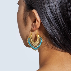 Detail of bohemian gold hollow heart earrings with blue turquoise beads on a model