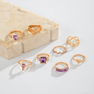 Detail of 8-piece gold-tone ring set featuring purple stones and geometric patterns