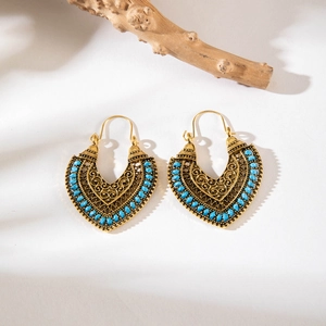 Detail of bohemian gold hollow earrings with blue beads and vintage floral patterns