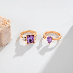 Detailed shot of two gold rings featuring square and teardrop purple gemstones